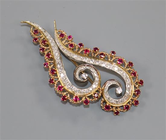 A modern yellow metal, ruby and diamond double scroll brooch, 65mm.